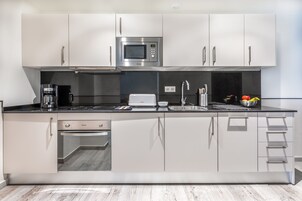 A modern kitchen with white cabinets, a stainless steel microwave, a coffee maker, and a toaster.