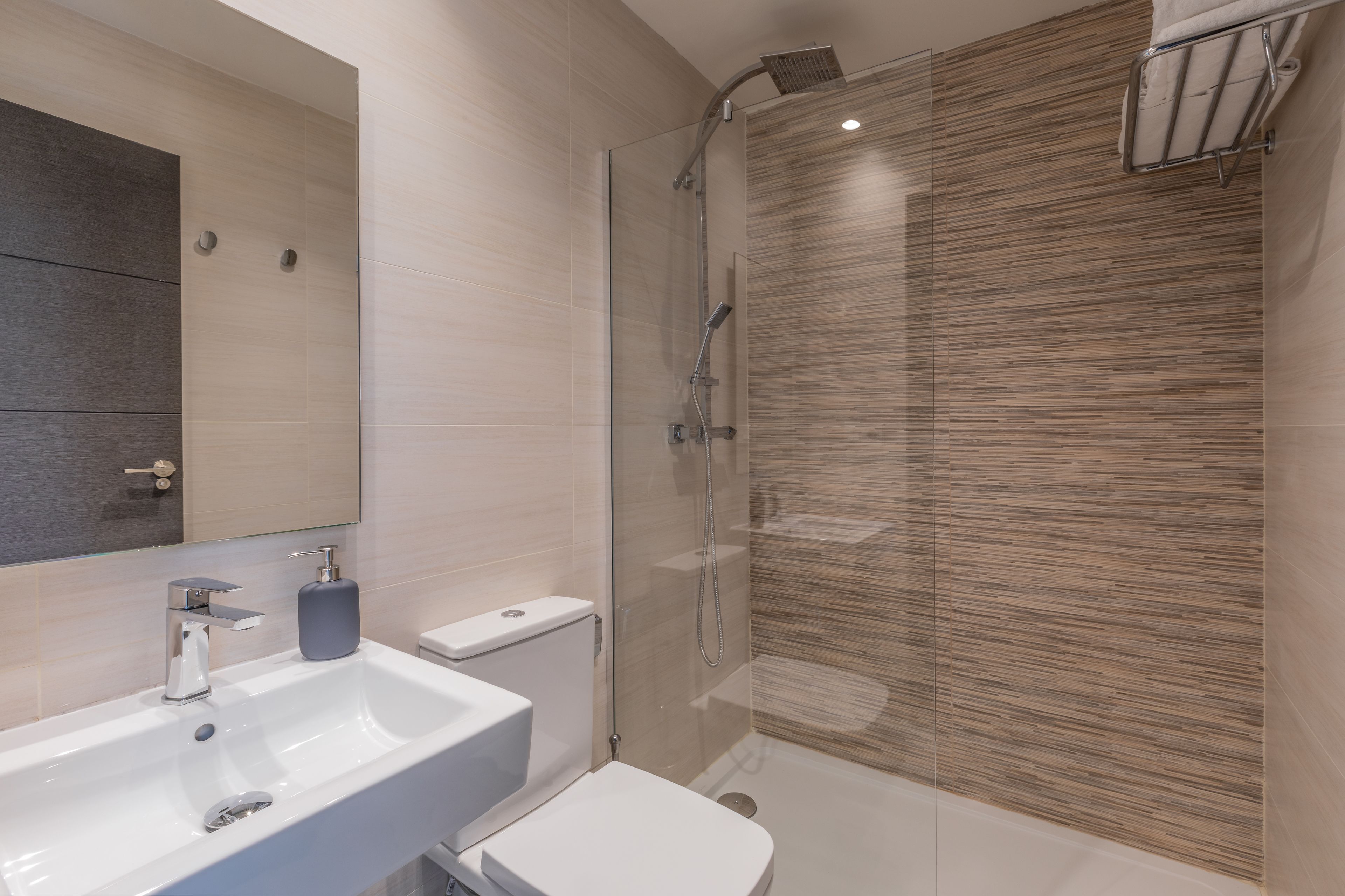A modern bathroom with a glass-enclosed shower, a white sink, and a toilet.