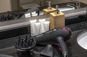 A bathroom vanity with a black countertop, a hairdryer, and a set of toiletries.