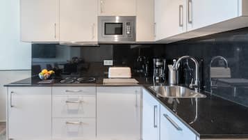 A modern kitchen with white cabinets, a black countertop, a built-in microwave, a toaster, and a sink.