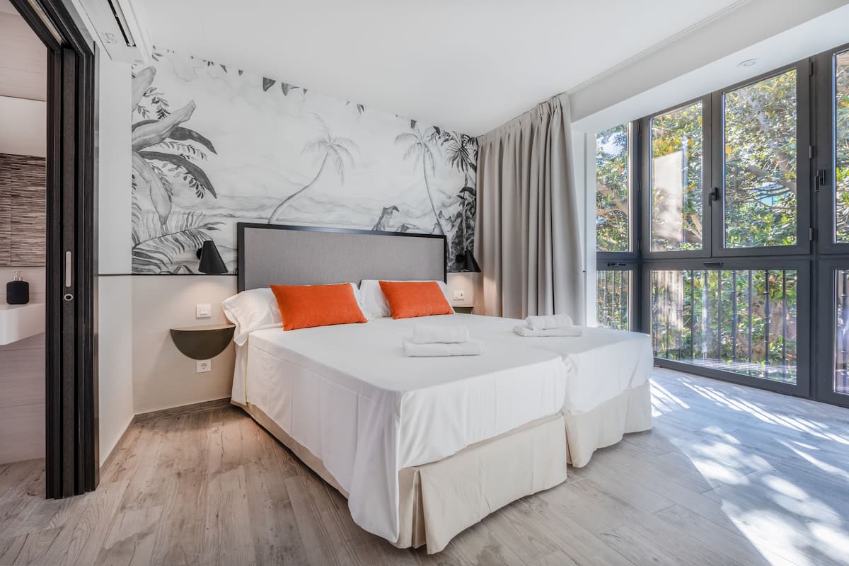 Une chambre d’hôtel moderne avec un grand lit, deux oreillers, une table de chevet et une fresque murale.