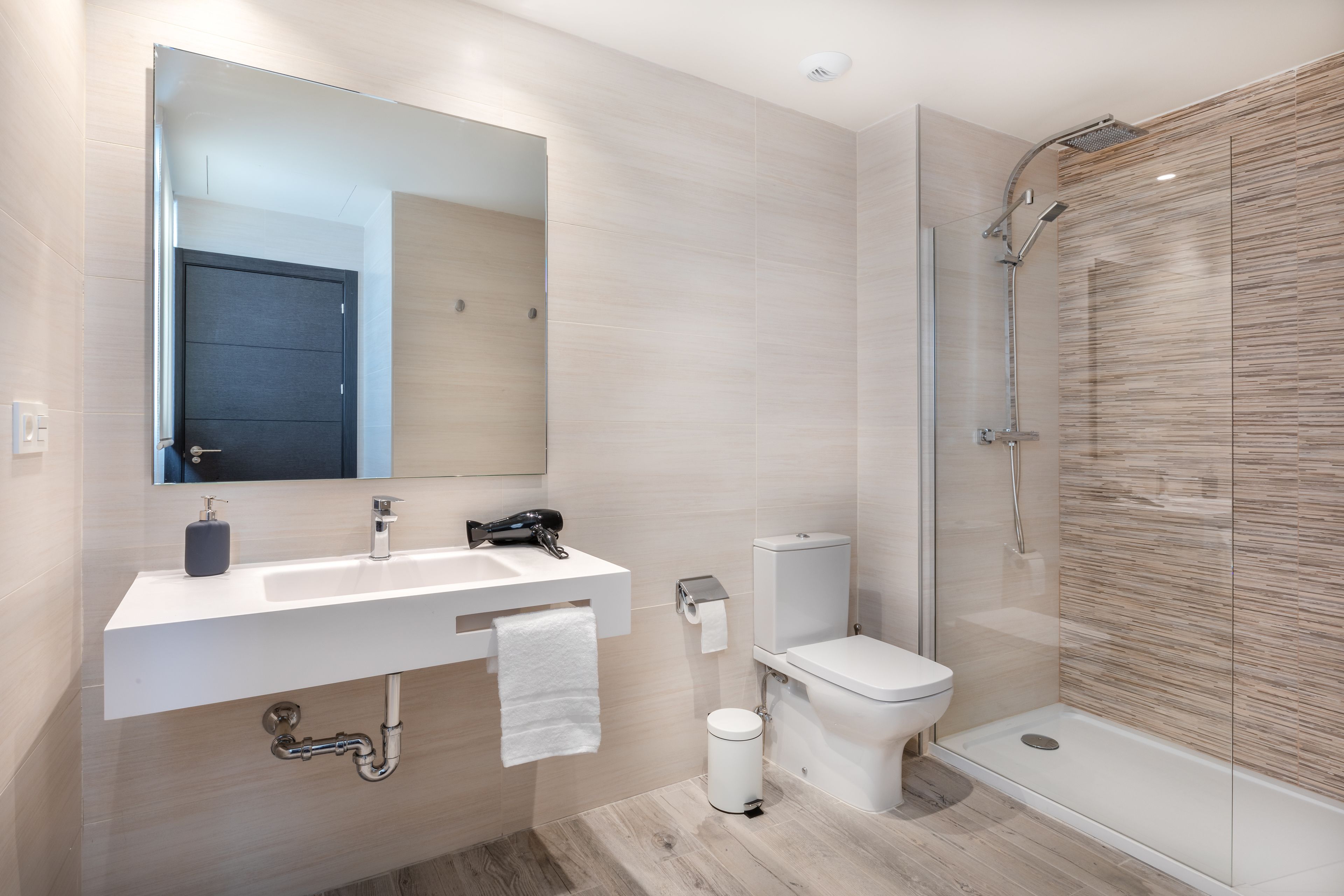A modern bathroom with a white sink, mirror, toilet, and shower.