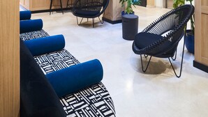 A modern lobby with hanging planters, blue and black patterned seating, and a wooden reception desk. - Slow Suites Setas (Seville)