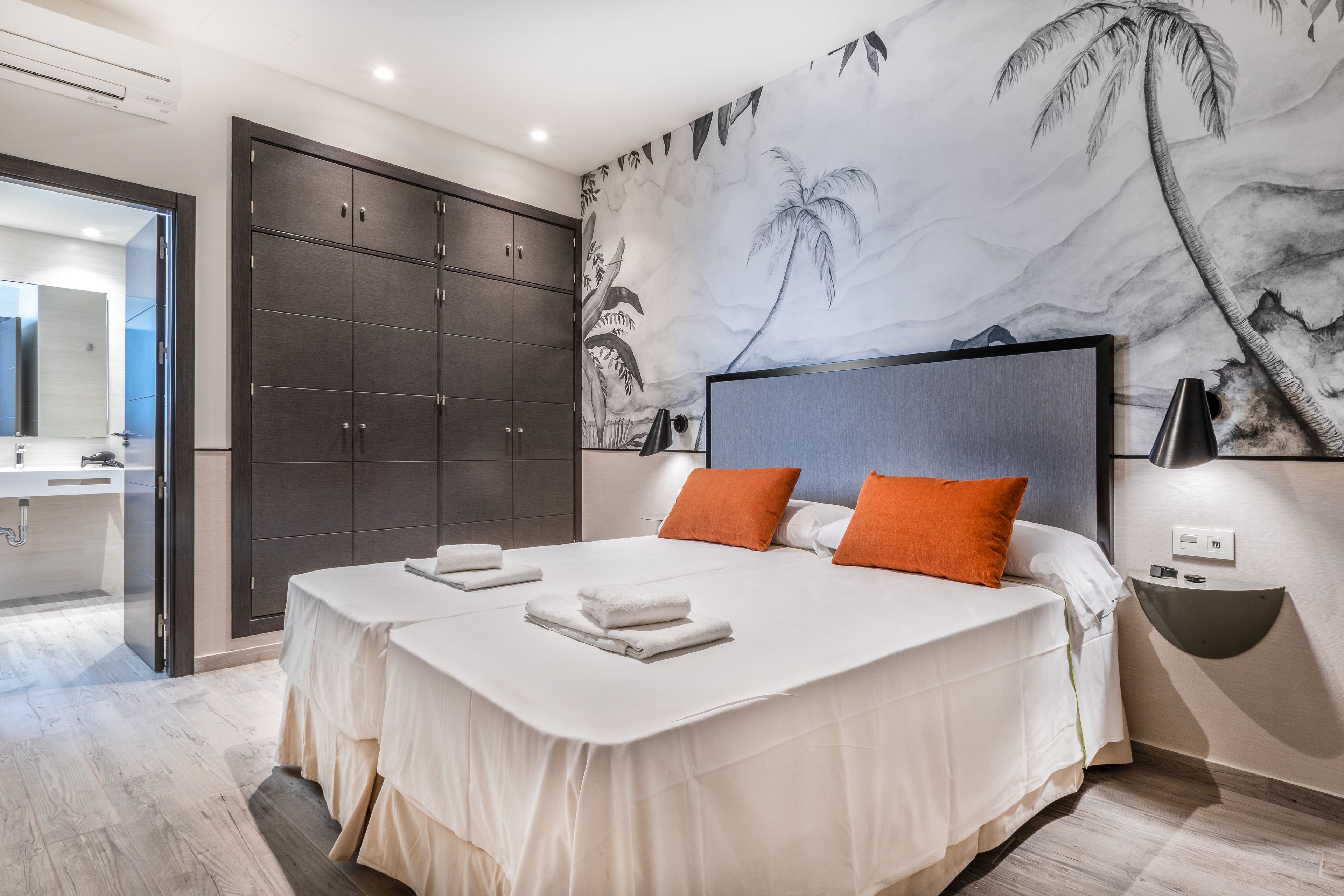 Een moderne slaapkamer met twee bedden, een grote garderobe en een tropische muurschildering.