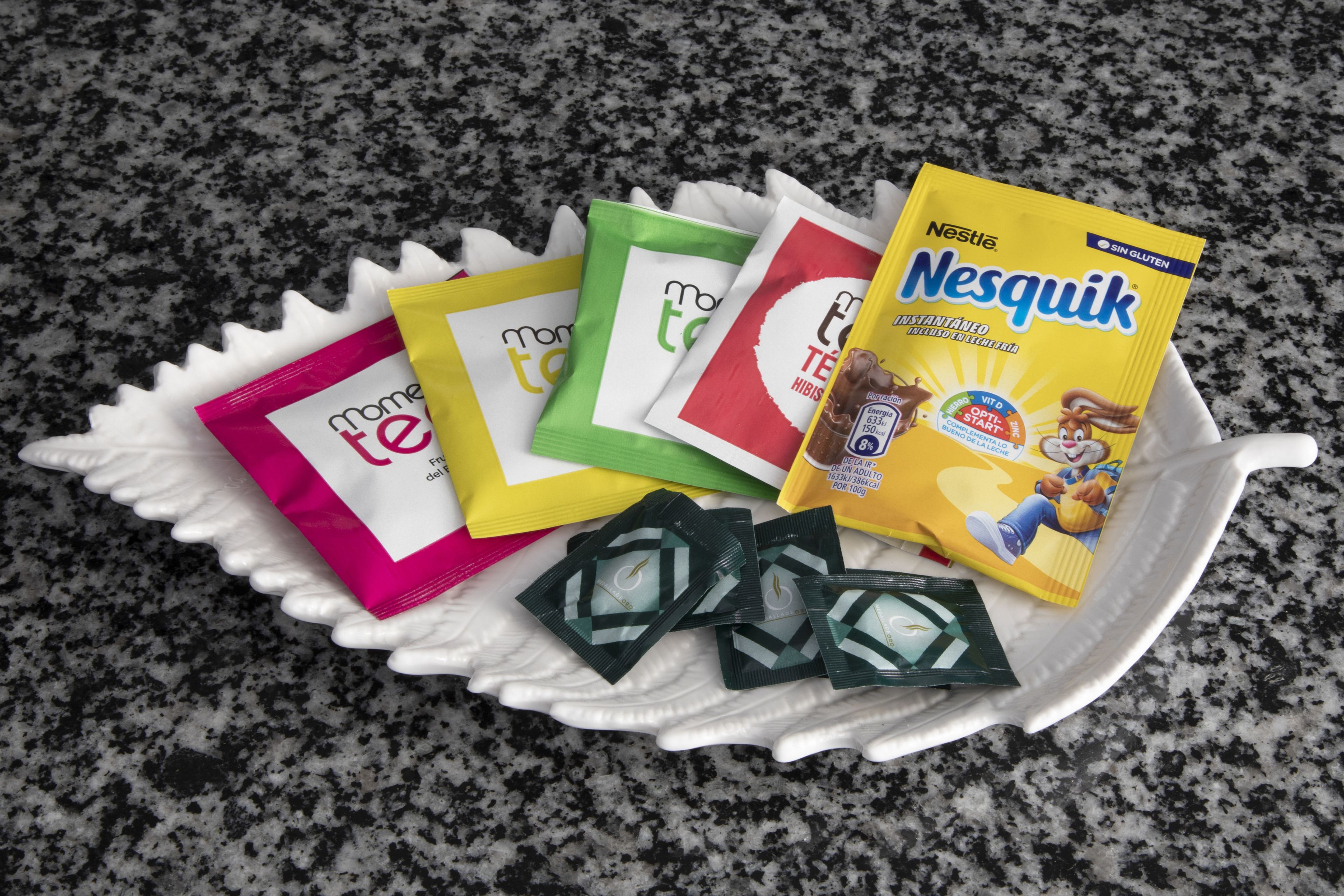 Uma bandeja com vários sachês de leite em pó para bebês, incluindo marcas como Nestlé e Moté.