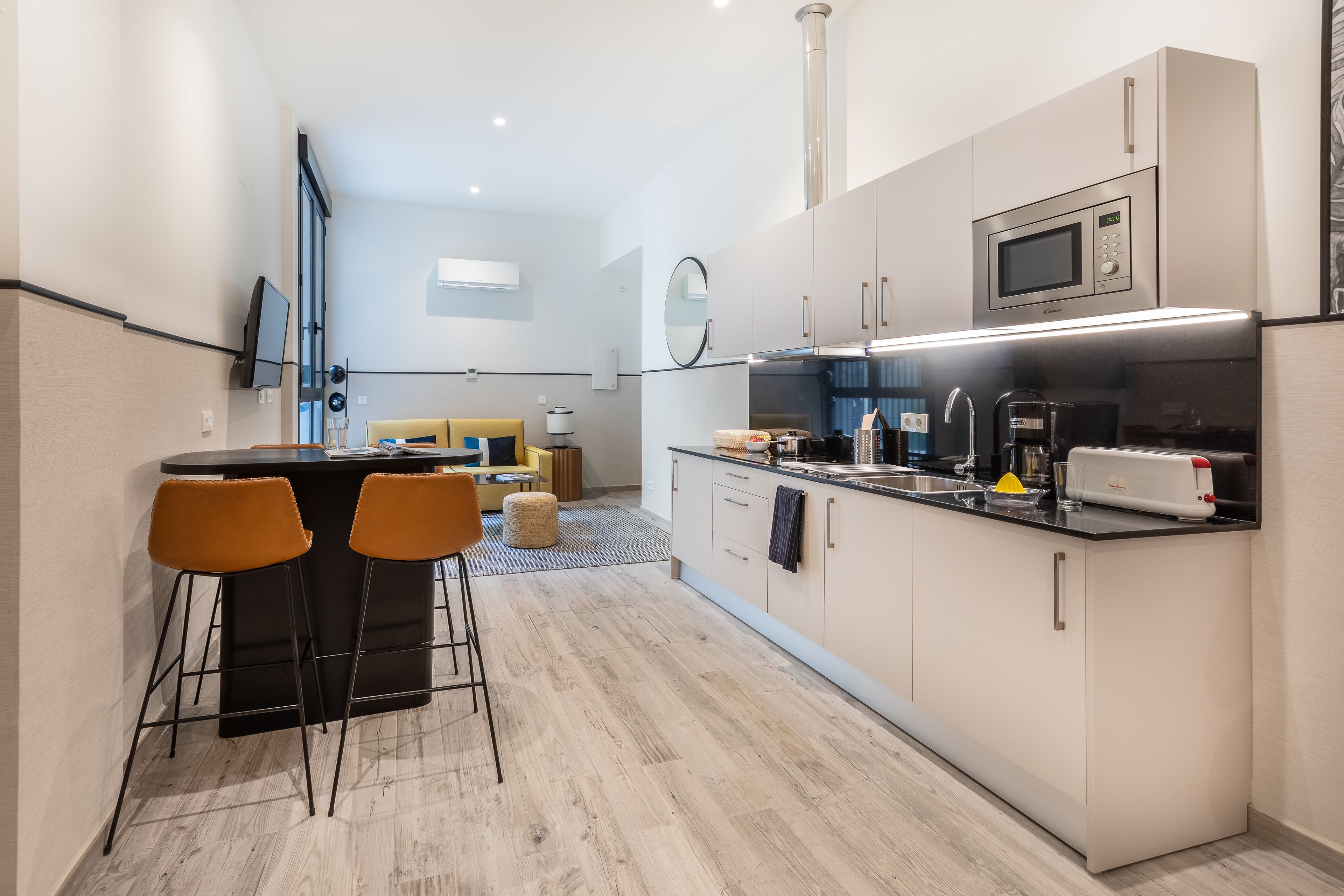 A modern kitchen with a central island, bar stools, and a microwave.