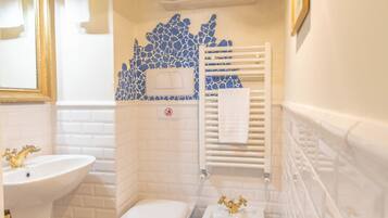 A bathroom with a white sink, two toilets, a bidet, a shower with blue mosaic tiles, and a white towel rack.