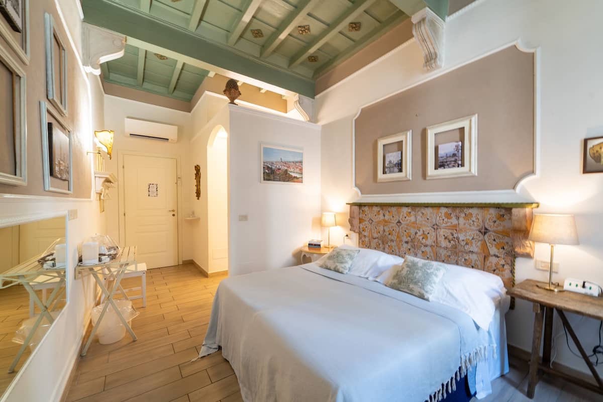 Een slaapkamer met een bed, nachtkastjes en een houten vloer.