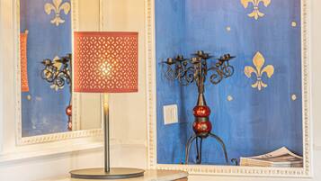 A room with a bed, a wooden dresser, a red patterned lamp, a candelabra, and a radiator.