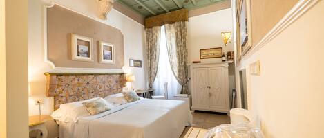 A bedroom with a bed, bedside tables, a dresser, and a window with curtains.