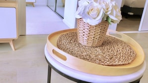A round wooden tray with a woven mat and a wicker basket containing white flowers. - Brilliant Victoria Harbour Waterfront Apartment (Docklands)