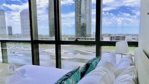 A hotel room with a large window offering a view of a marina and tall buildings. - Brilliant Victoria Harbour Waterfront Apartment (Docklands)