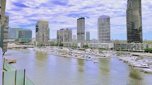 A marina with multiple yachts docked, surrounded by modern high-rise buildings. - Brilliant Victoria Harbour Waterfront Apartment (Docklands)