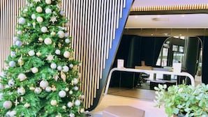 A Christmas tree with ornaments, a glass table, and seating areas in a modern lobby. - Brilliant Victoria Harbour Waterfront Apartment (Docklands)