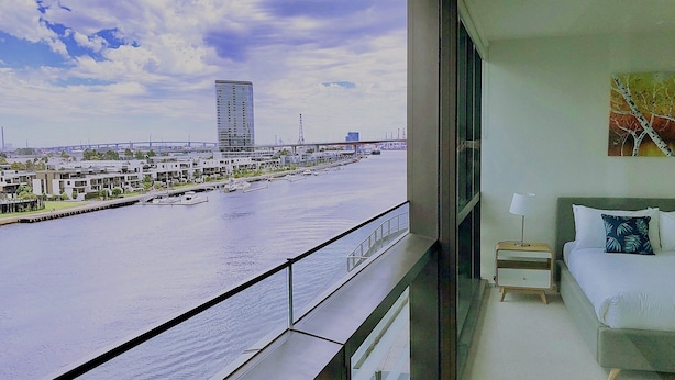 A hotel room with a large window overlooking a marina and a cityscape. - Brilliant Victoria Harbour Waterfront Apartment (Docklands)