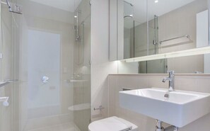 A modern bathroom with a glass-enclosed shower, a white sink, and a mirror above the sink. - Brilliant Victoria Harbour Waterfront (Docklands)