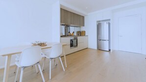 A modern kitchen with white cabinetry, a wooden countertop, and a built-in oven. There are two white chairs and a small table. - Brilliant Victoria Harbour Waterfront (Docklands)