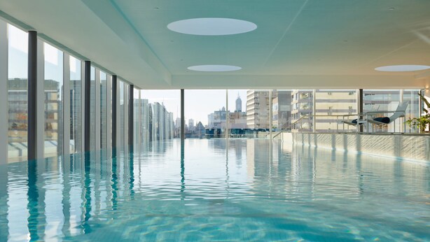 An indoor swimming pool with clear water, large windows, and a view of the cityscape. - Fawkner Apartment 1B1B (Melbourne)