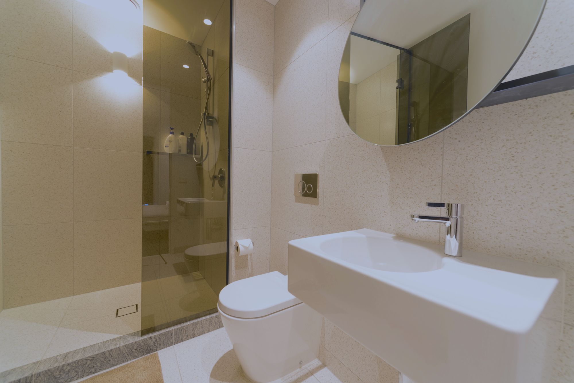 A modern bathroom with a glass-enclosed shower, a white toilet, and a freestanding bathtub.