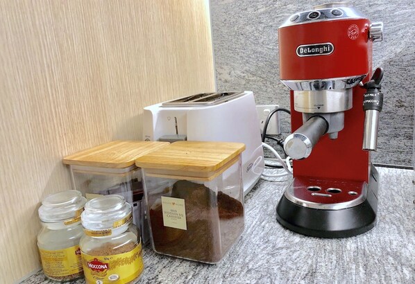 A coffee maker, a toaster, and two containers of coffee on a kitchen counter.