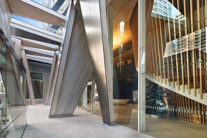 Un bâtiment moderne doté d’une architecture originale, caractérisée par des panneaux de verre inclinés et des éléments décoratifs en bois.
