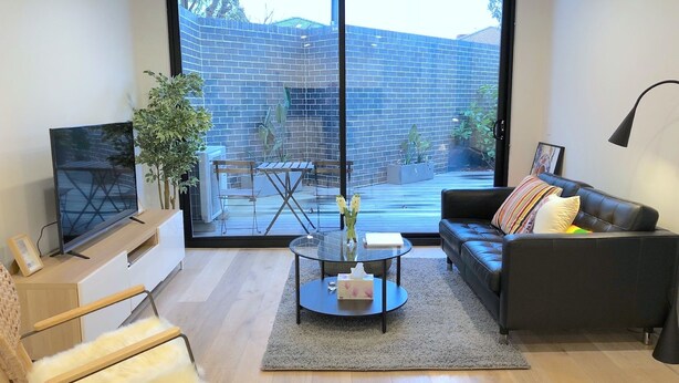 A modern living room with a large sliding glass door leading to an outdoor patio.
