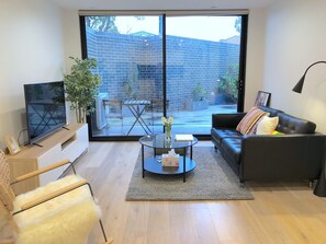 A modern living room with a large sliding glass door leading to an outdoor patio.