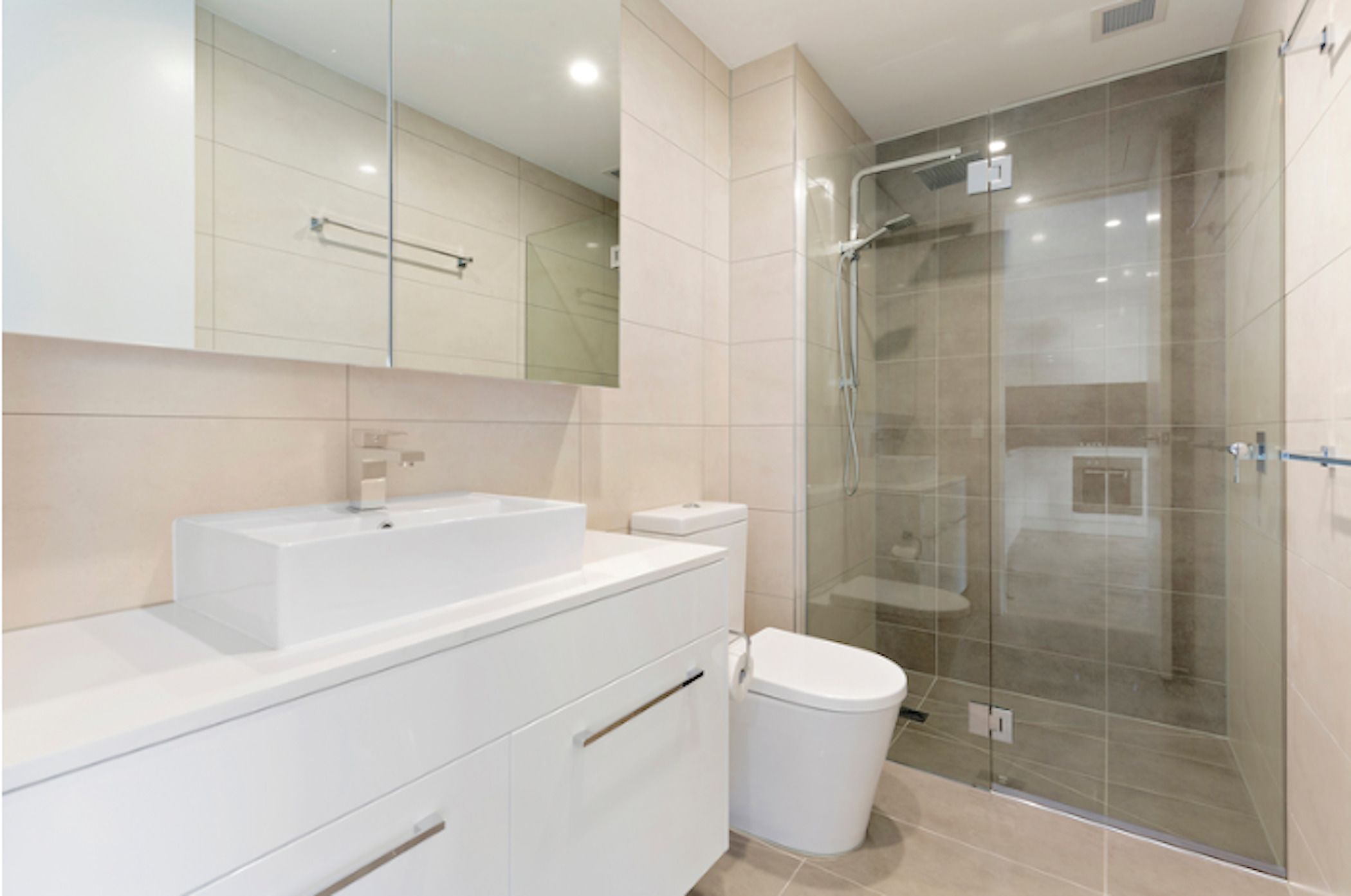 A modern bathroom with a glass-enclosed shower, a white sink, and a toilet.