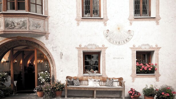 A building with a stone facade, a large arched entrance, and a bench outside. - Der Hoferwirt (Neustift Im Stubaital)