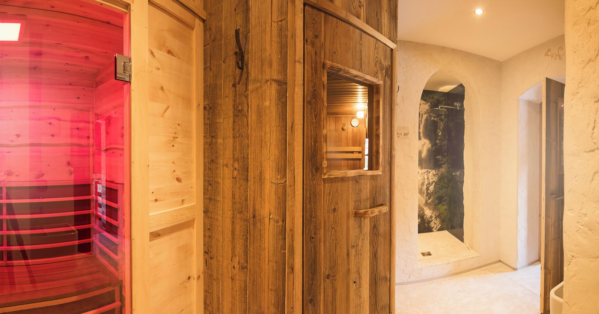 Un interior de madera con una sala de sauna, una puerta de madera y una pared de piedra con un cuadro enmarcado.