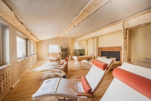 Una habitación con piso de madera, chimenea y varios sillones reclinables.