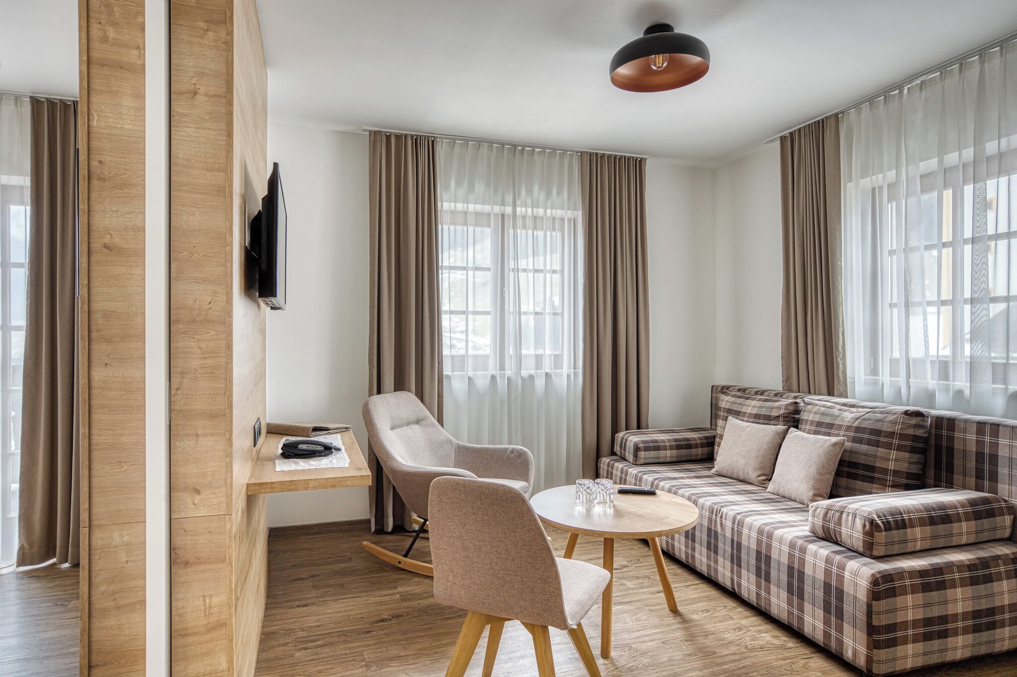 Una sala de estar moderna con un escritorio de madera, un sofá y una silla.