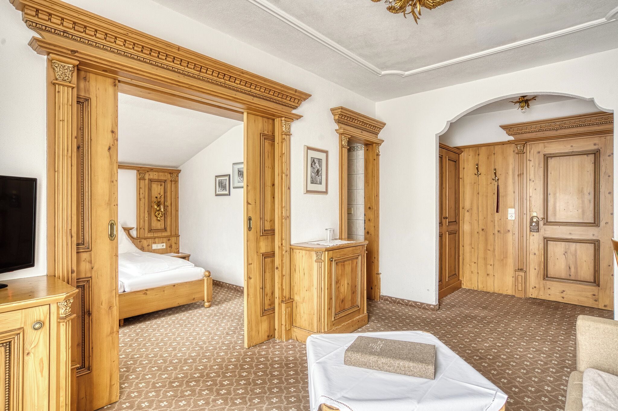 Een hotelkamer met een houten bed, een televisie, een bureau en een kledingkast.