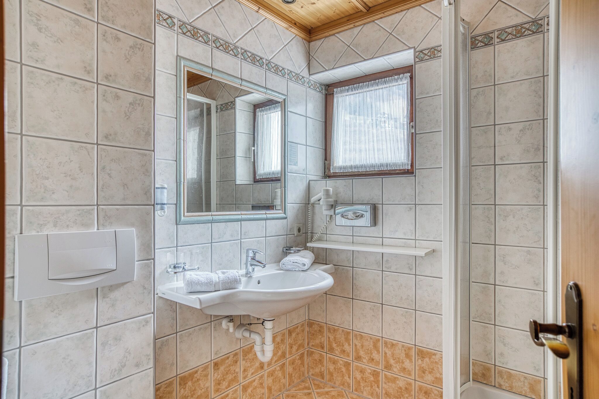 A bathroom with a sink, mirror, and shower.
