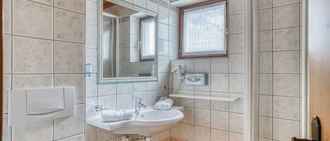 A bathroom with a sink, mirror, and shower.