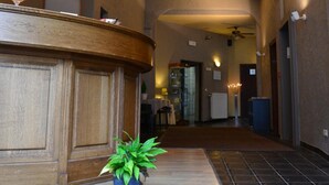 A reception area with a wooden counter, a potted plant, and a tiled floor. - Hotel De Franse Kroon (Diest)