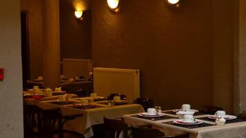 A restaurant with tables set for dining, featuring a ceiling fan and wall-mounted lighting.