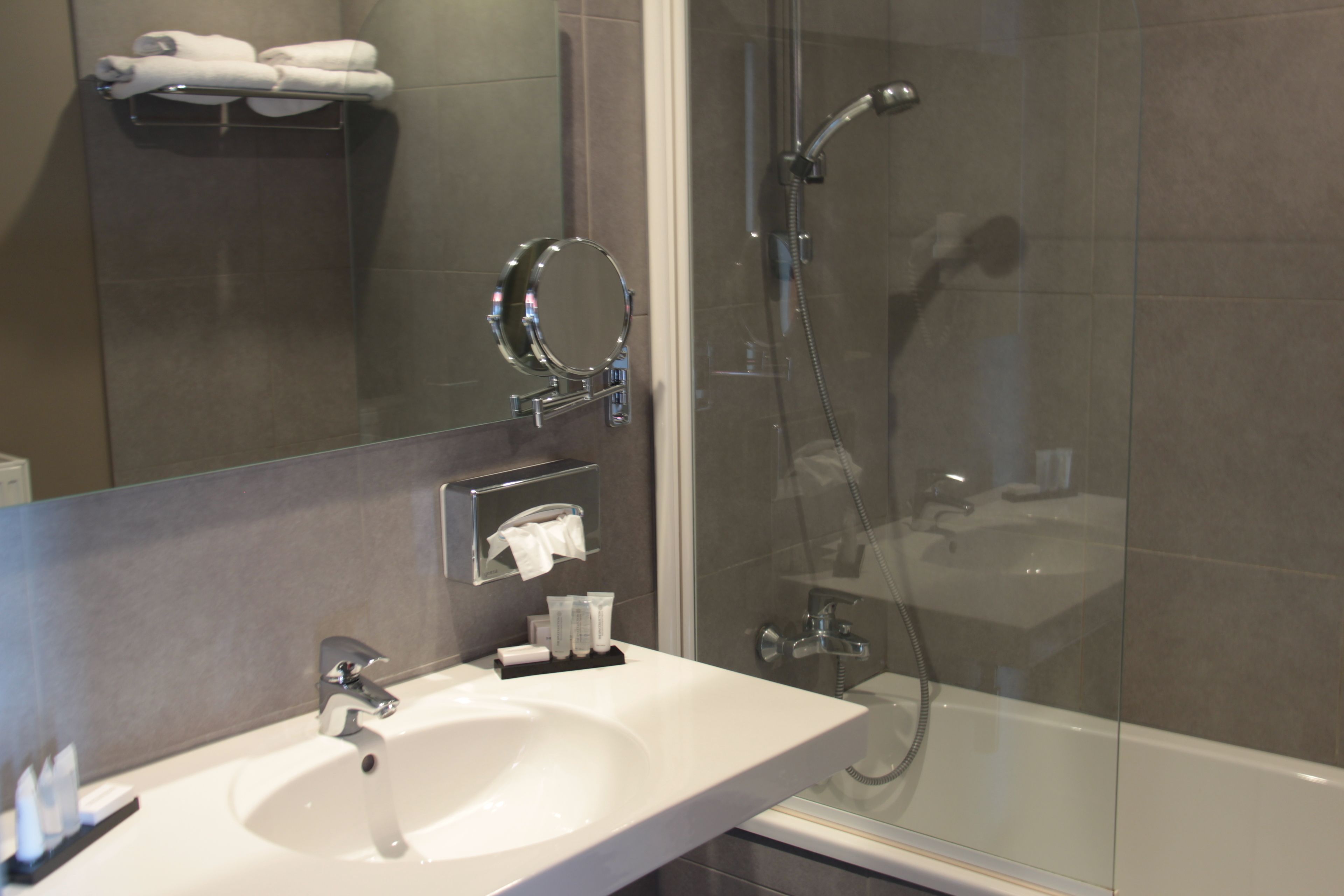 Een moderne badkamer met een wit wastafelmeubel, een spiegel, een handdoekhouder en een douchecabine met glazen wanden.