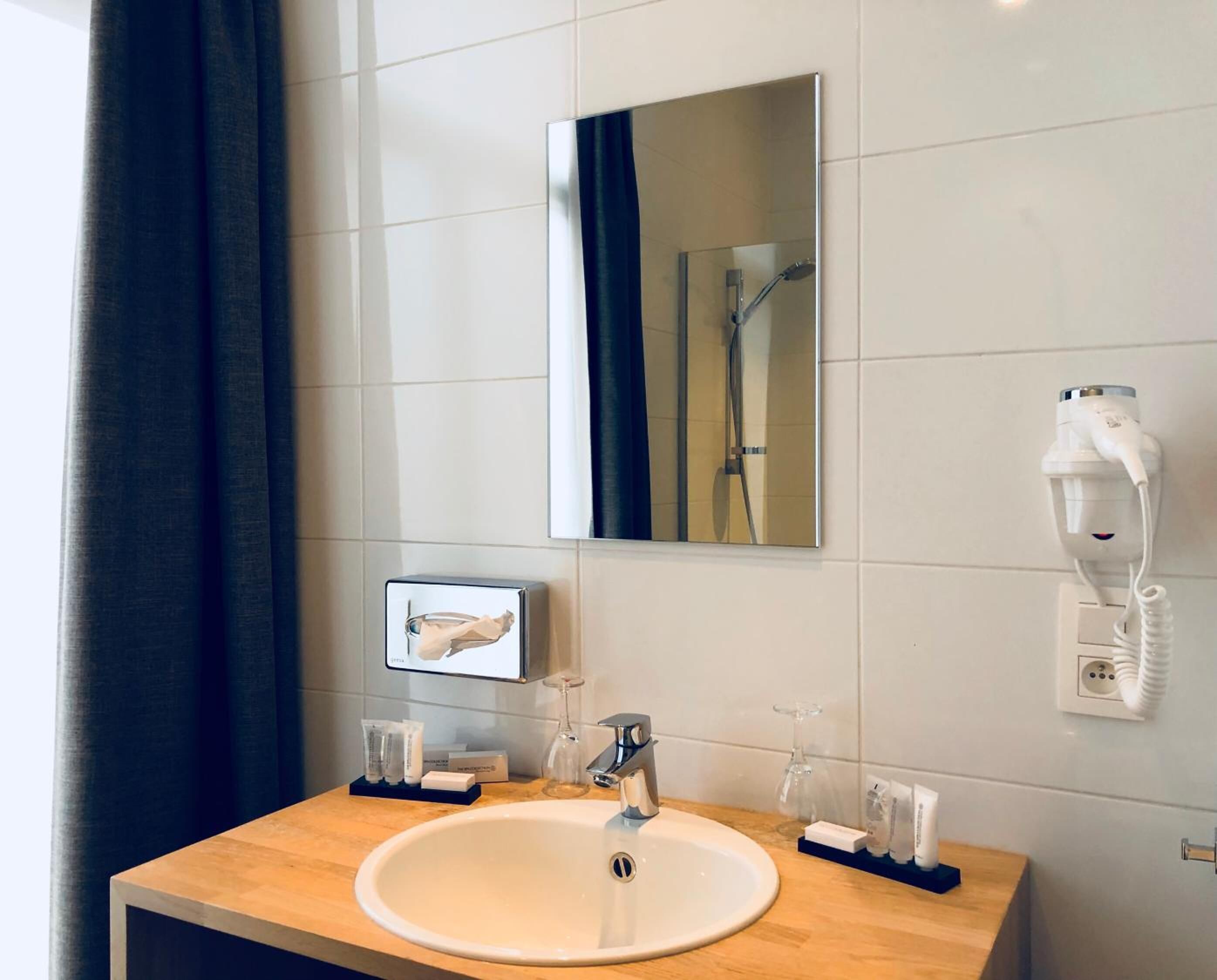 Une salle de bain avec un lavabo, un miroir et un porte-serviettes.