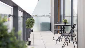 Un balcone moderno con porta in vetro, piante in vaso e tavolo con sedie.