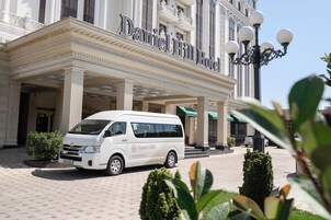 A white van parked in front of the Daniel Hill Hotel with a classical facade and columns.