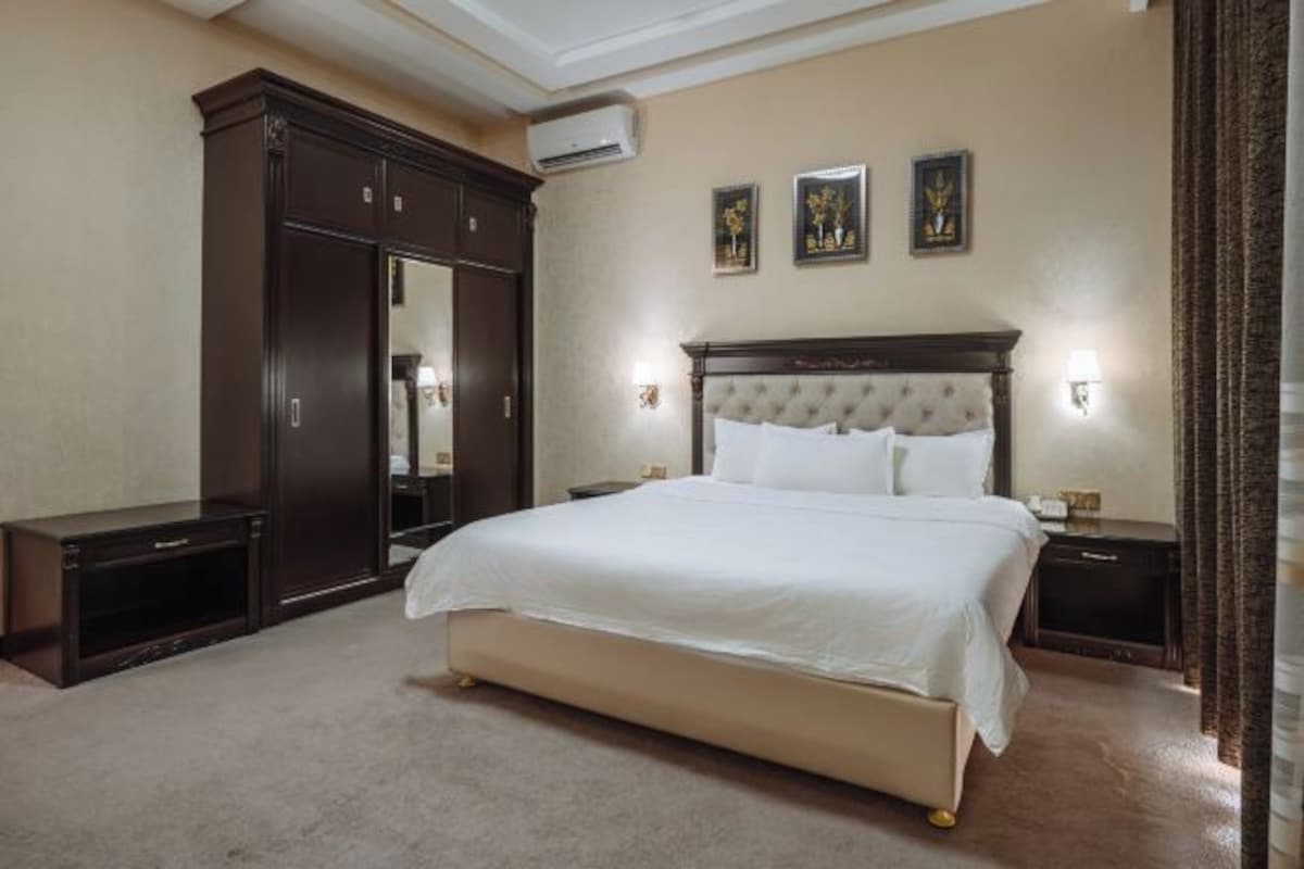 Ein Schlafzimmer mit einem großen Bett, einem dunklen Holzschrank und einer Wand-Klimaanlage.