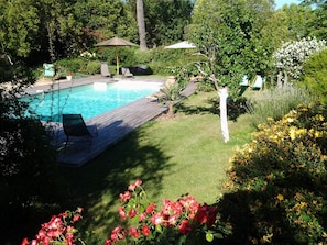A backyard with a swimming pool, lounge chairs, and a wooden deck. - Chambres d'hôtes Les Douves (Saint-Thomas)