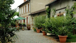 Ein Innenhof mit Kieswegen, Topfpflanzen und einem Gebäude mit Ziegeldach.