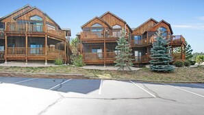 A row of wooden cabins with balconies, a parking lot, and a small Christmas tree.