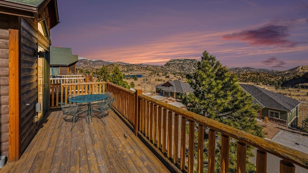 A wooden deck with a table and chairs, overlooking a mountainous landscape. - Teepee Mountain 12a 2 Bedroom Condo by RedAwning (Estes Park)