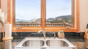 A kitchen with a double sink, wooden window frames, and a view of mountains. - Teepee Mountain 12a 2 Bedroom Condo by RedAwning (Estes Park)