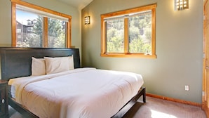 A bedroom with a large bed, two windows, a ceiling fan, and a nightstand. - Mount Cairns 16a 2 Bedroom Condo by RedAwning (Estes Park)