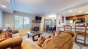 A living room with a fireplace, a television, and a dining area with chairs and a table. - Horizons 4 165 Updated Condo, Walk to Town, On Shuttle Route to Lodges by RedAwning (Mammoth Lakes)