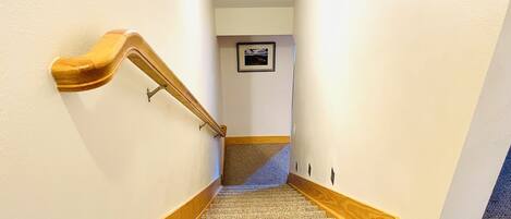 Un escalier recouvert de moquette, avec des rampes en bois et un cadre photo accroché au mur.